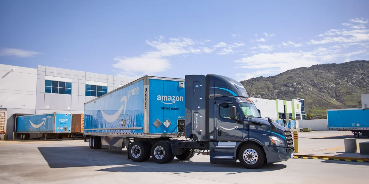 Amazon semi-trucks parked in a large logistics yard at dusk.