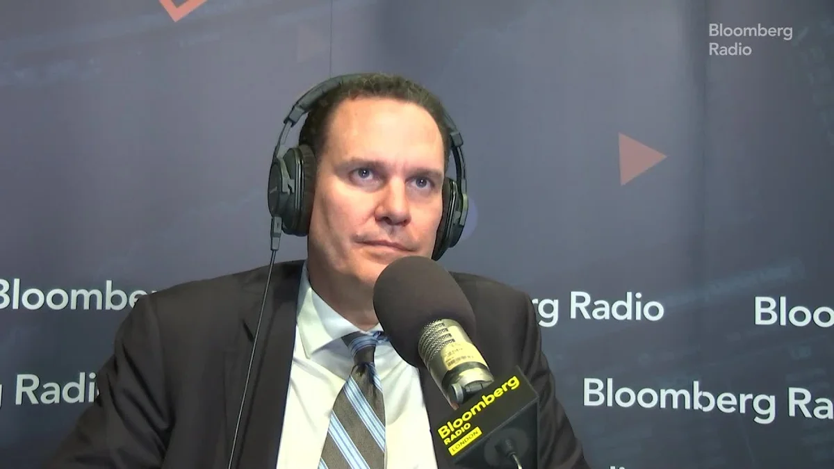 Man wearing headphones and suit in front of a microphone at Bloomberg Radio.