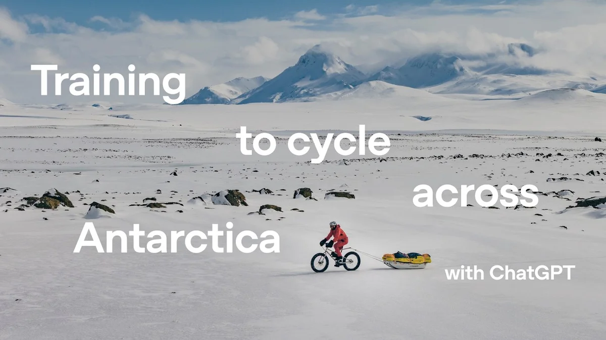 A person in a red suit cycling across a vast, snowy landscape with mountains in the background.