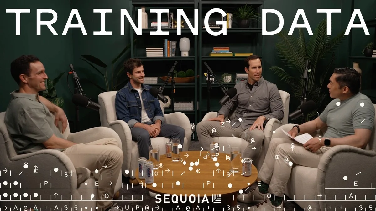 Four people sitting in chairs around a coffee table in a studio setting.