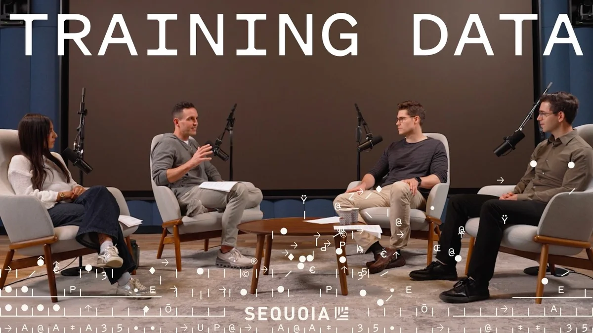 Four people sitting in chairs in a discussion setting, microphones present.